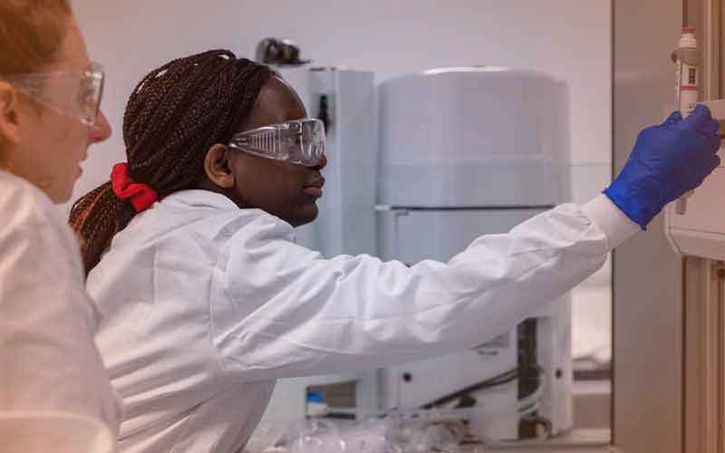 Two female researchers in a lab looking at a tube of liquid
