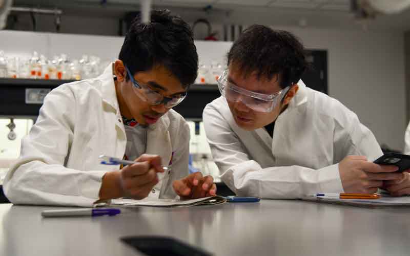 Two people in lab coats working together at a table