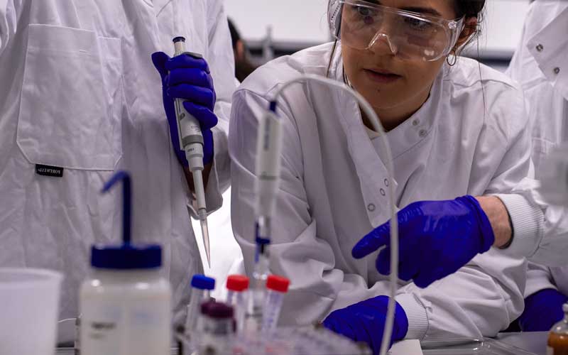Close up of student in lab coat and protective glasses